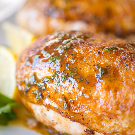 Skin on roasted chicken breast bathed in pan sauce.