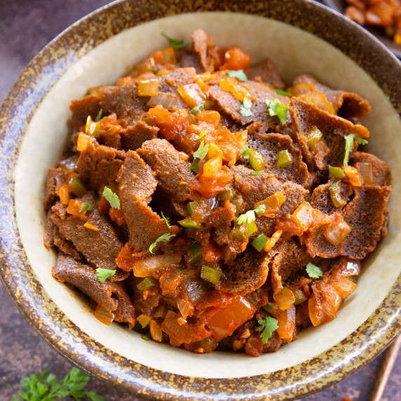 Closeup of a bowlful of firfir (sauteed teff injera)