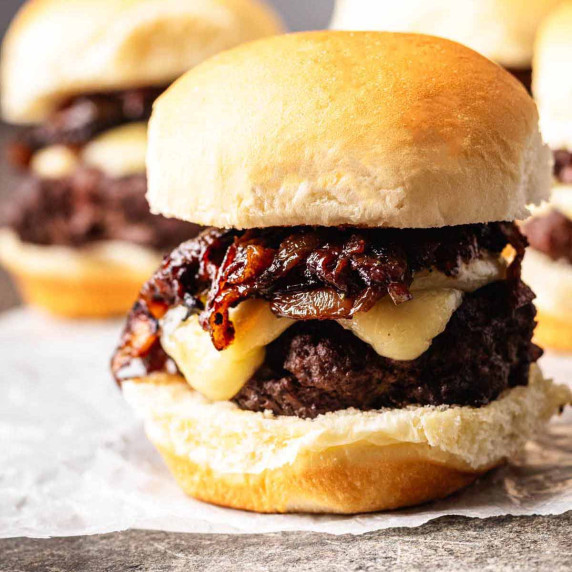 Close-up of a French onion slider with caramelized onions and melted cheese on a toasted bun, with m
