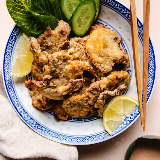 Fried oyster mushrooms, sliced lemons, cucumber and bibb lettuce on white plate with blue border