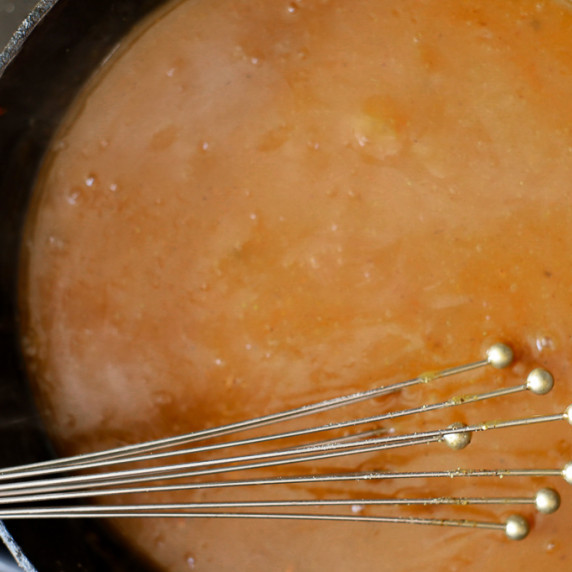 Beef Gravy in a cast-iron skillet with a whisk in the pan for stirring 