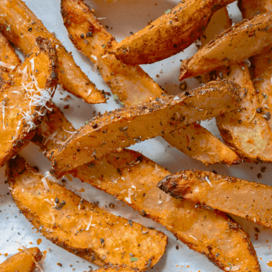Crispy golden-brown roasted potato wedges seasoned with herbs, pepper, grated Parmesan shavings