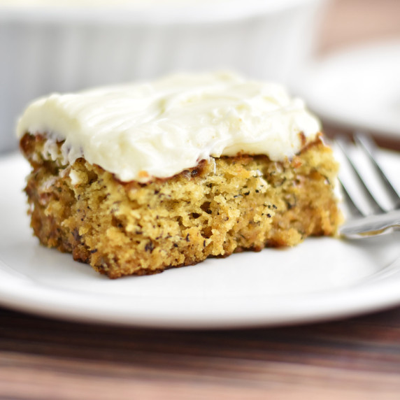 A slice of gluten free banana cake and fork on a small white plate.