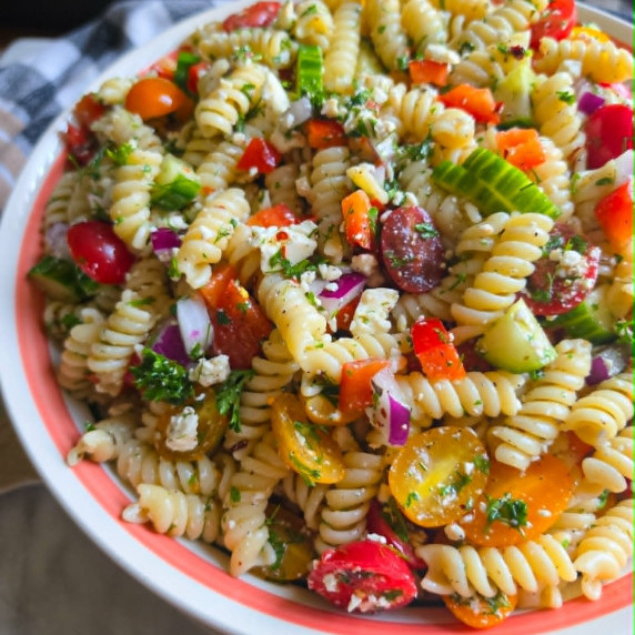 A bowl of pasta salad loaded with colourful veggies & herbs.
