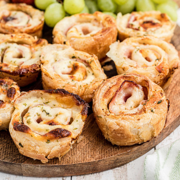 Close up of some ham and cheese bites on a board.