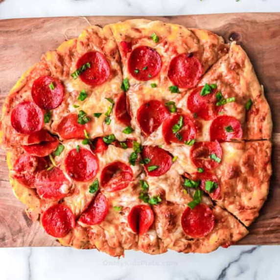 Close up of pepperoni pizza on a cutting board.