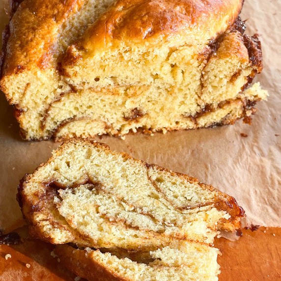 Close up of a cinnamon swirl bread slice, on a brown cutting board. 