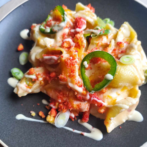 Golden shells topped with green jalapeno sliced, red Hot Cheetos, and a white drizzle of ranch.