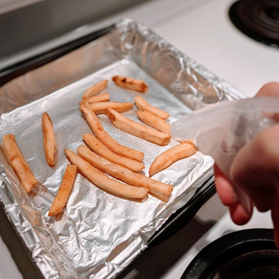 fries on a tray being misted with a spray bottle filled with water