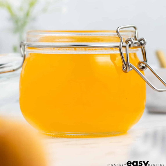 Sweet peach syrup in a glass jar on a white countertop