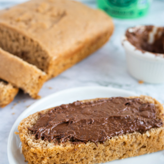 Slice of bread covered in chocolate with a pint of ice cream in the background
