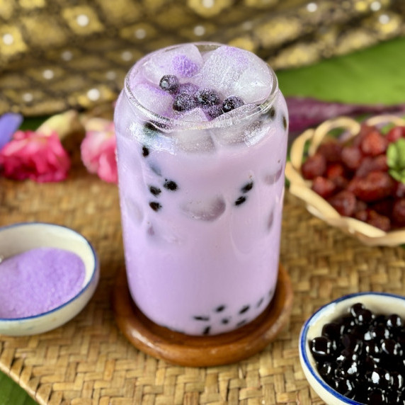 Taro milk tea boba in a glass with tapioca pearls and taro powder.