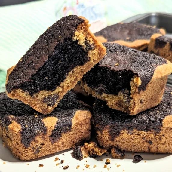 A pile of brookie bars with one broken in half sitting on top.