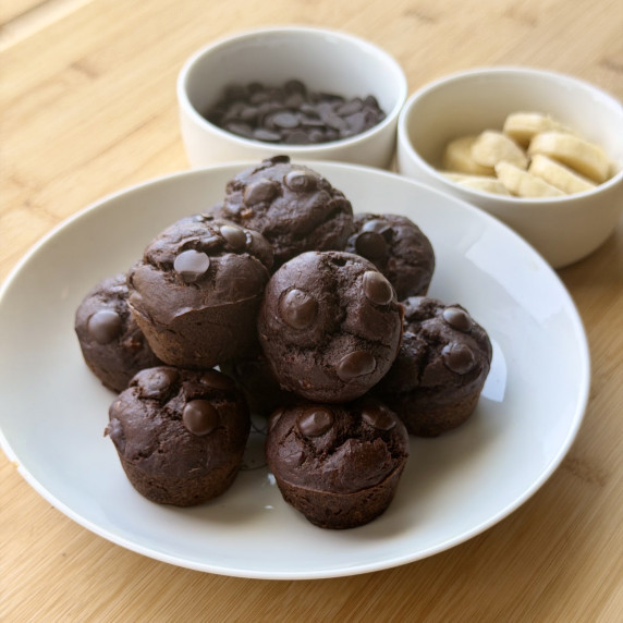 Chocolate Banana Muffins on a plate with chocolate chips and bananas 