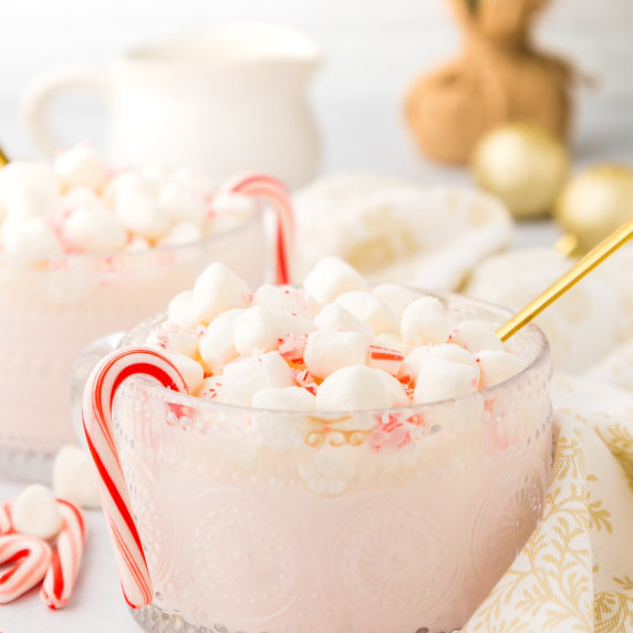 white peppermint hot chocolate in a mug with candy canes and marshmallows