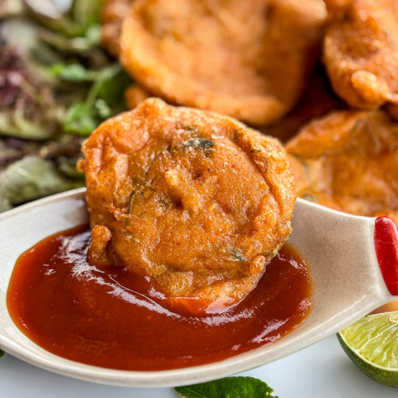 Close-up of Thai fish cake (tod mun pla) dipped in sweet chili sauce.