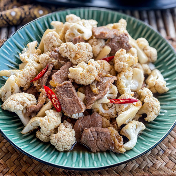 Close-up of cauliflower beef stir-fry in a green dish.