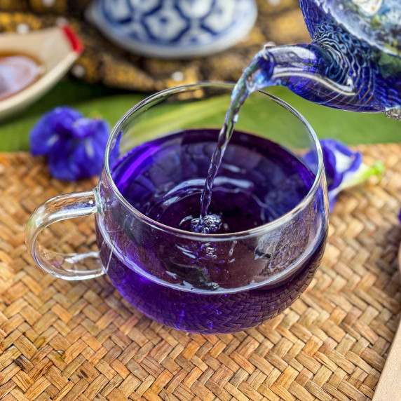 Butterfly pea tea poured into a glass from a teapot.