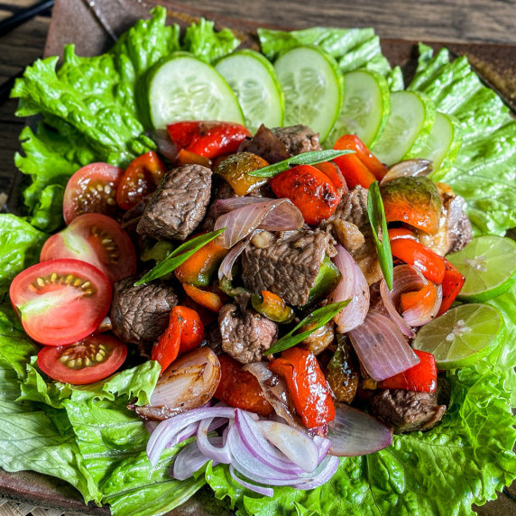Close-up of Vietnamese shaking beef salad served with vegetables.