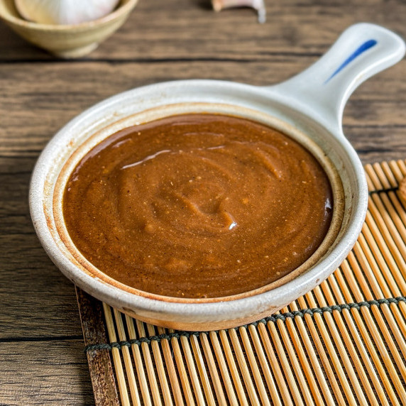 Close-up of hoisin sauce in a clay sauce bowl on a bamboo placemat.