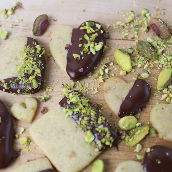 chocolate dipped pistachio cookies with cup of tea of side.