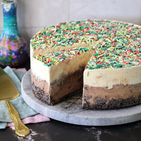 Ice cream cake on a marble serving board with one slice cut, ready to serve.