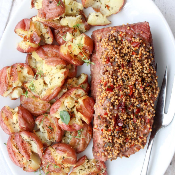 White plate with corned beef and smashed potatoes