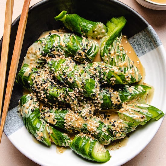 Sliced Japanese cucumber and sesame dressing on a white plate with chopsticks