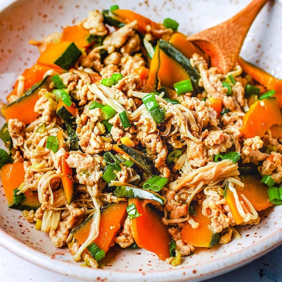 Kabocha squash, chicken and mushrooms on a stoneware plate with a spoon