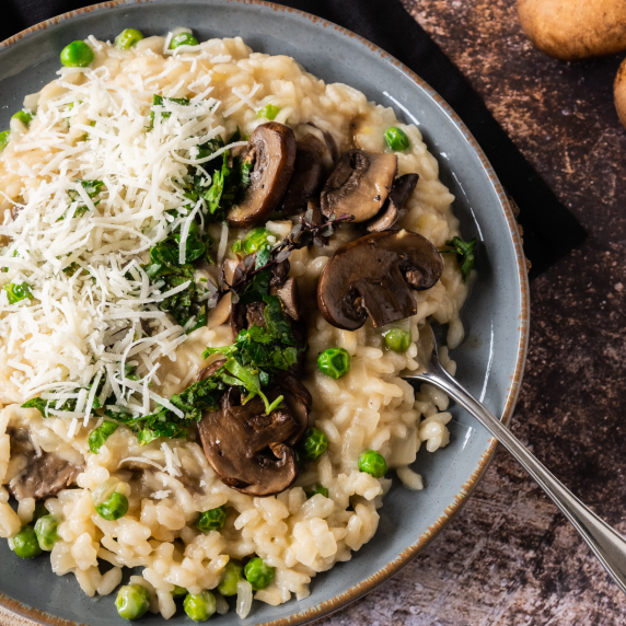 Lamb Broth Mushroom and Pea Risotto with Gremolata, in bowl on wodden surface.