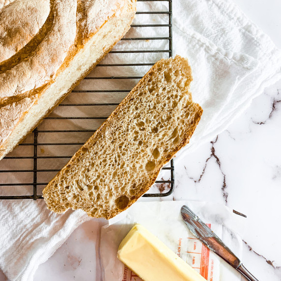 Slice of sourdough bread next to the loaf with butter