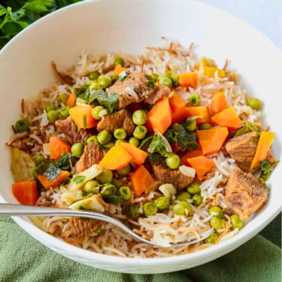 Bizella, a Lebanese stew with beef, peas, and carrots, served over rice with vermicelli in a bowl.