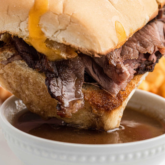 Close up of a prime rib sandwich being dipped into au jus.