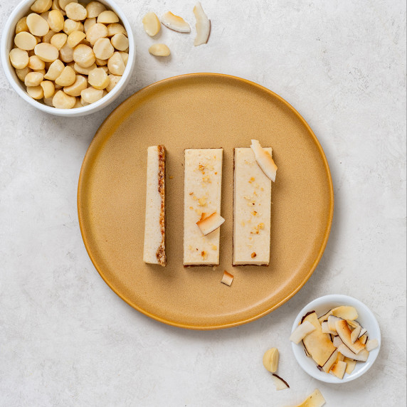 Lemon macadamia slices arranged on an orange plate on a white countertop