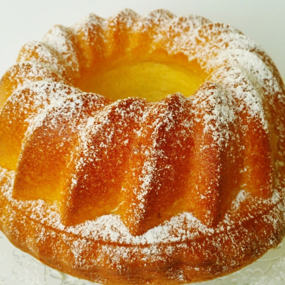 Golden lemon chiffon cake with a light dusting of powdered sugar, served on a glass cake stand