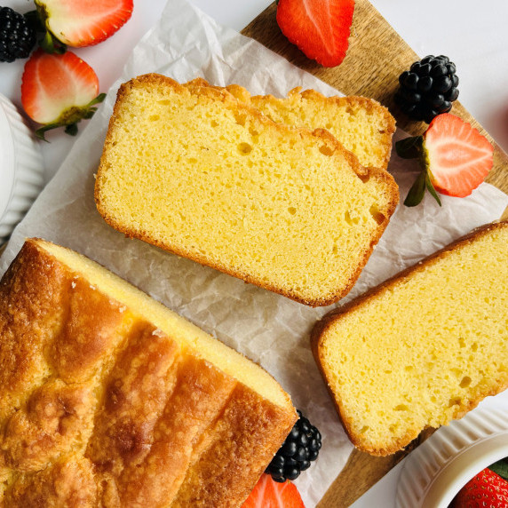 Slices of pound cake on a cutting board with fresh blackberries, raspberries and strawberries.