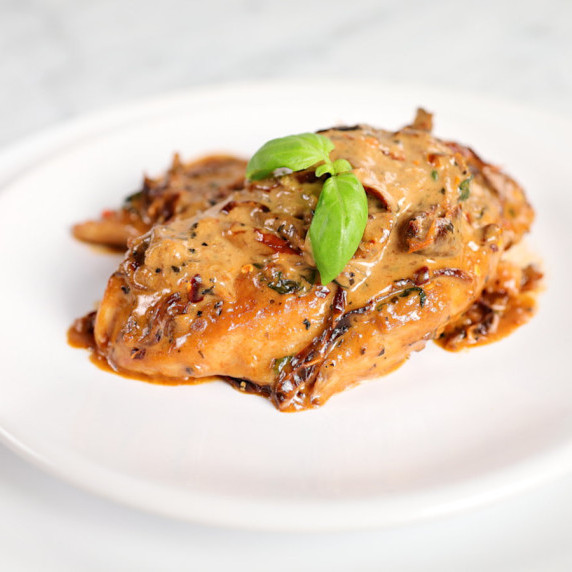 Elegantly plated serving of keto Marry Me Chicken garnished with fresh basil leaves.