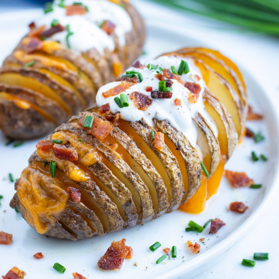 Thanksgiving Side Dish RECIPE; cheesy hasselback potato served on a white dish