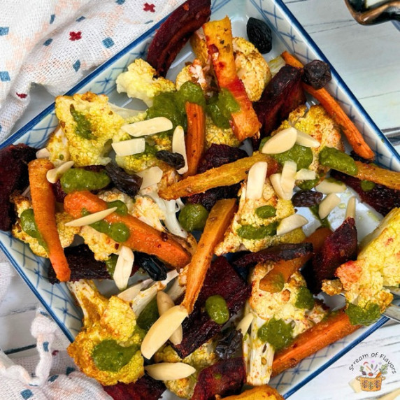 Moroccan Roasted Cauliflower Salad with carrots, beets, chermoula, almonds, raisins, and spices on a