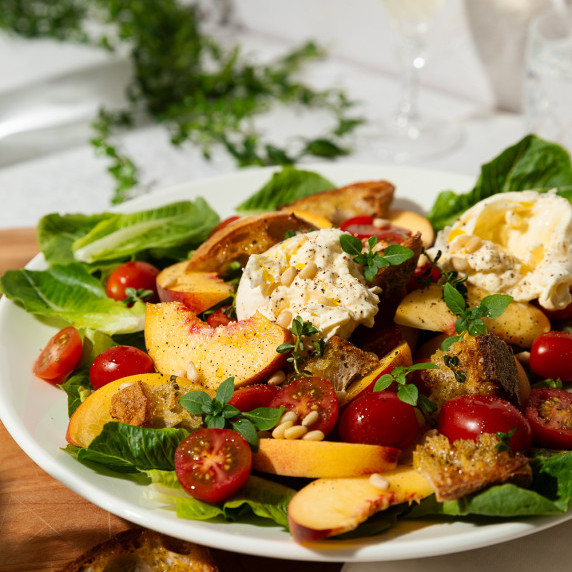 A large salad on a platter surrounded by bread slices and a container of salad dressing