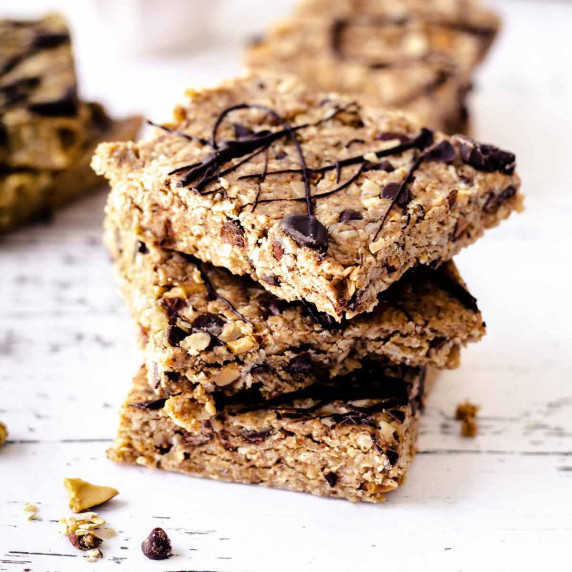 Stack of no bake oatmeal peanut bars on a weathered white wood surface