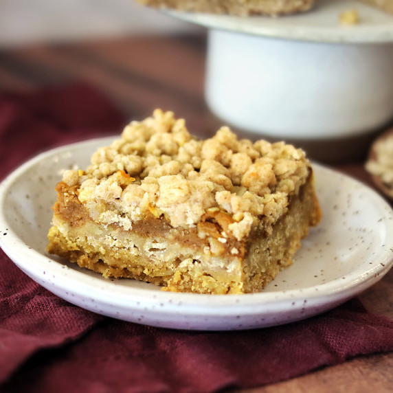Oatmeal Crumble Pumpkin Pie Bar on a small speckled plate with a burgundy linen napkin.