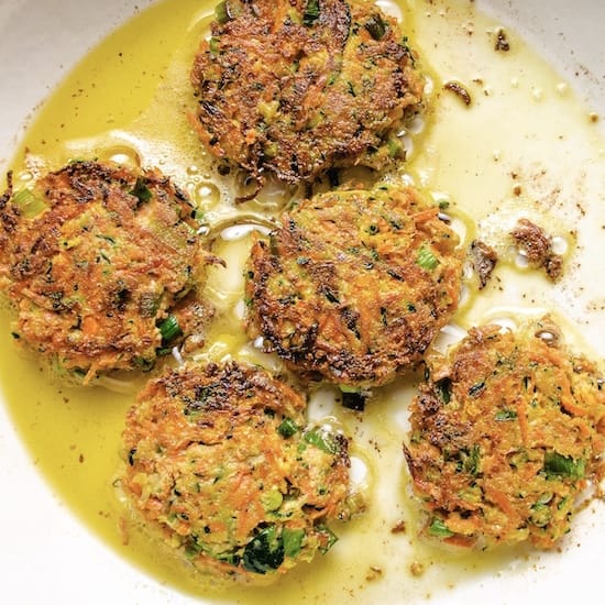 Zucchini carrot fritters and olive oil on a white plate