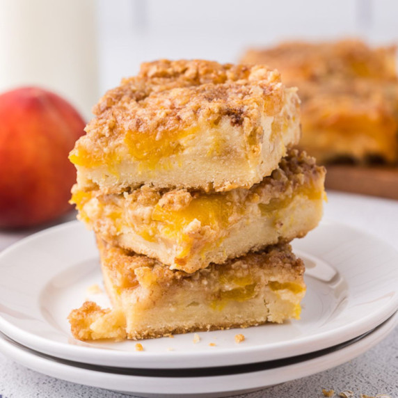 Peach bars stacked on a white plate.