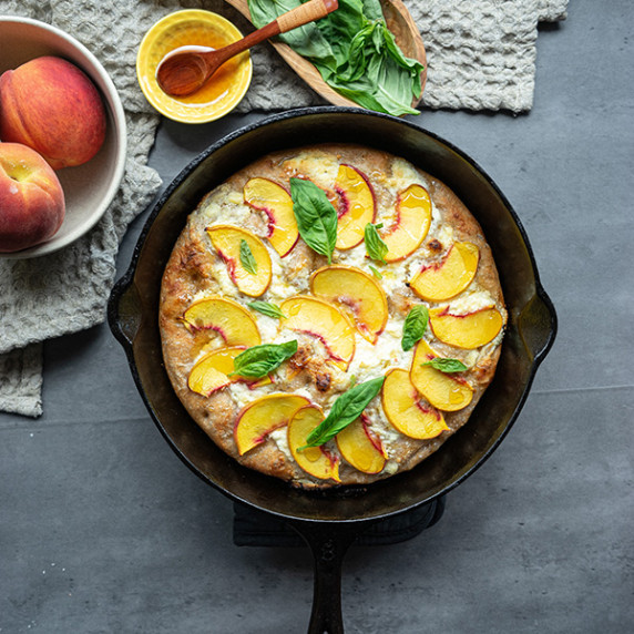 Slices peaches nicely arranged over a freshly bakes focaccia bread with ricotta 