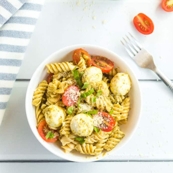 Pasta with mozzarella, tomatoes and pesto in a bowl.