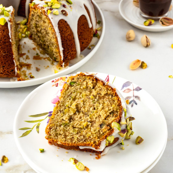 Slice of glazed pistachio bundt cake on small dish.