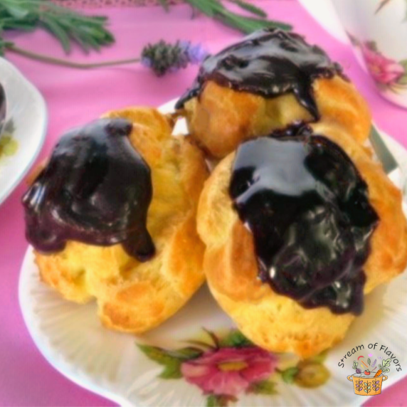 French Profiteroles with buttercream and chocolate icing on a white plate