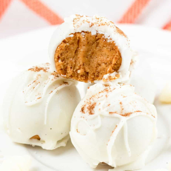Pumpkin cheesecake bite stacked on top of two others coated in white chocolate.