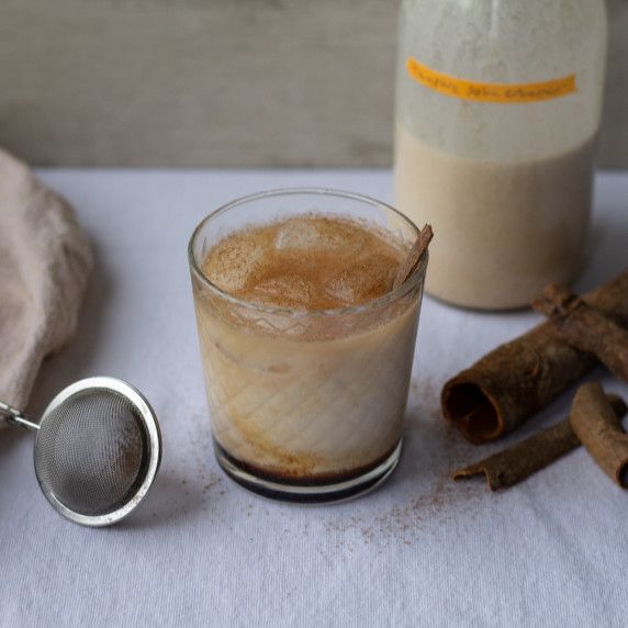 pumpkin spice white russian with cinnamon sticks in a short glass